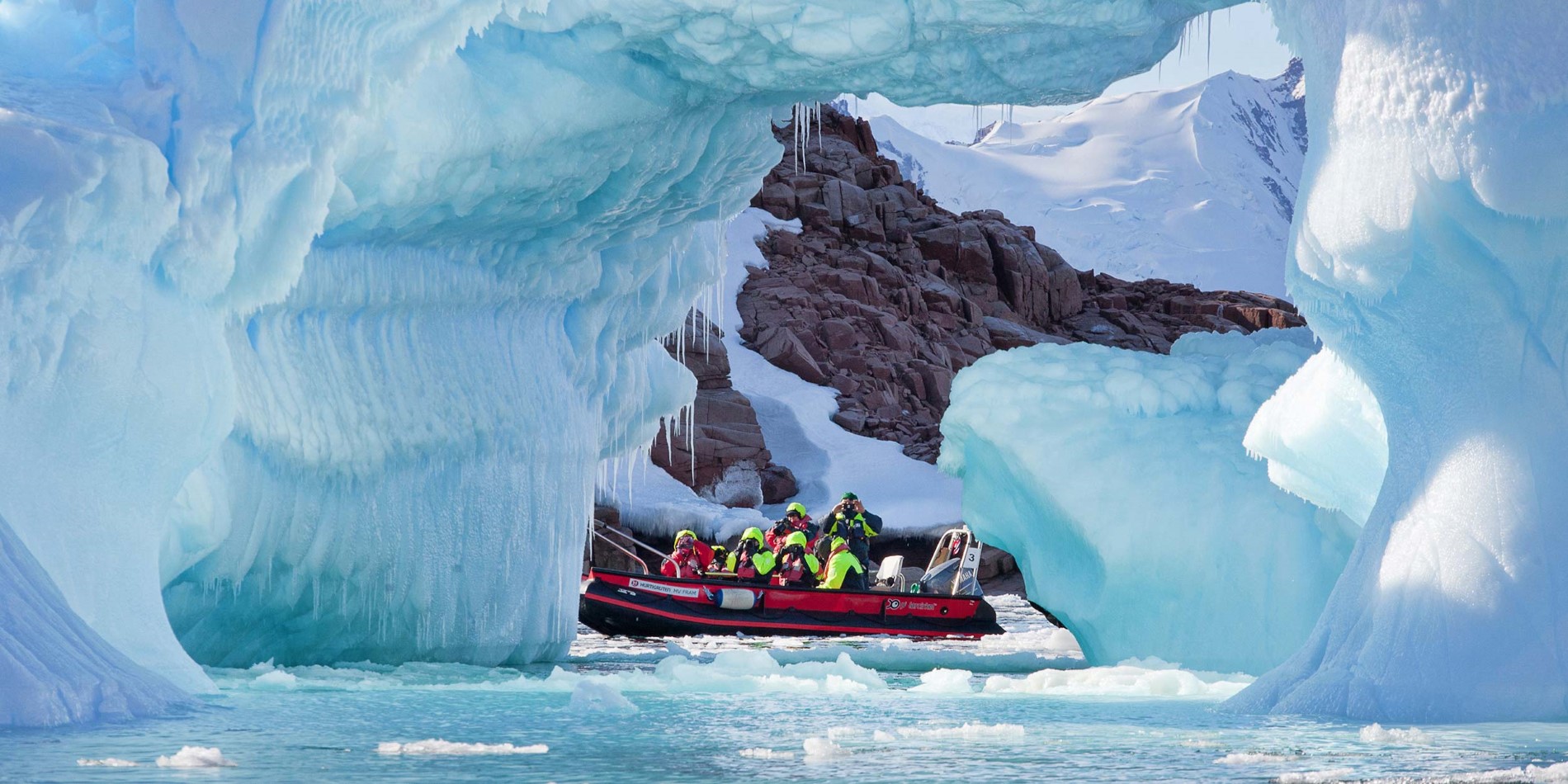Group of tourists in small boat among spectacular ice formations